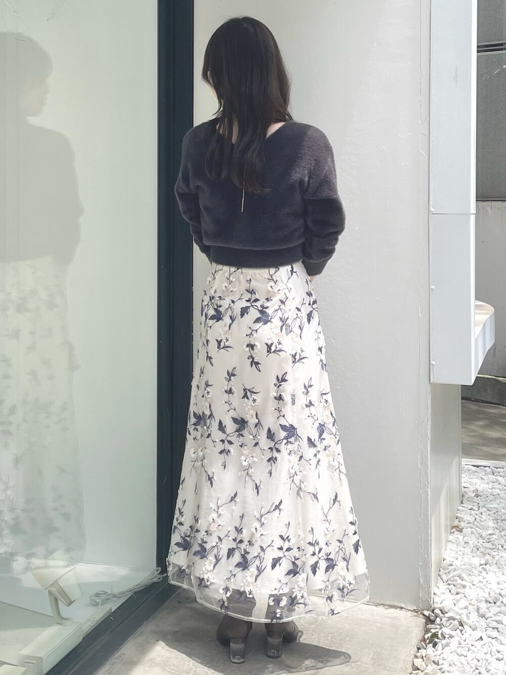 ブラック系のハンドバッグ、ブラウン系のブーツ、グレー系のスカートを着用したレディースの秋コーディネートの3枚目の写真