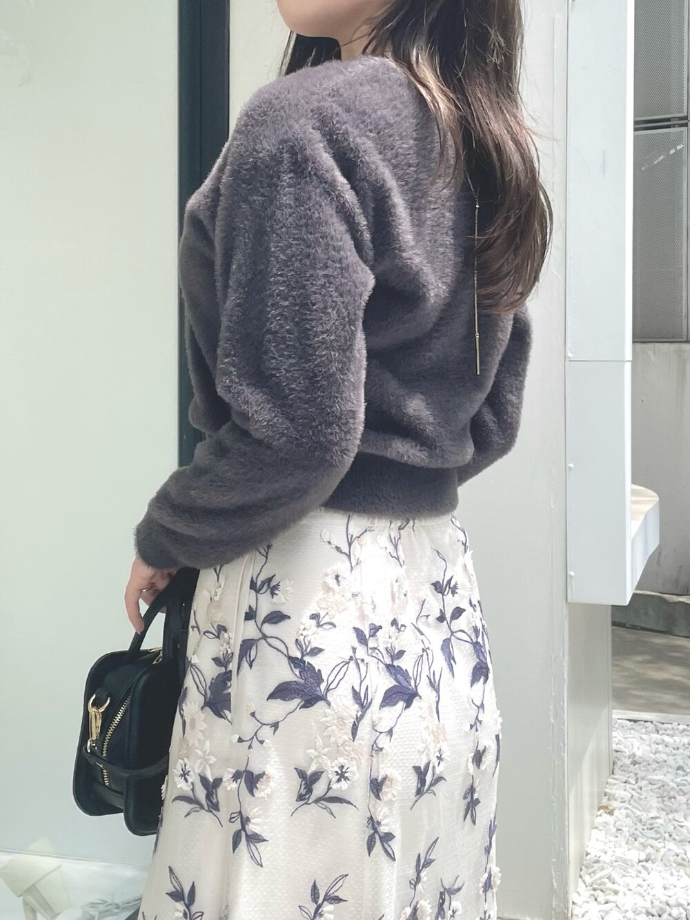 ブラック系のハンドバッグ、ブラウン系のブーツ、グレー系のスカートを着用したレディースの秋コーディネートの5枚目の写真