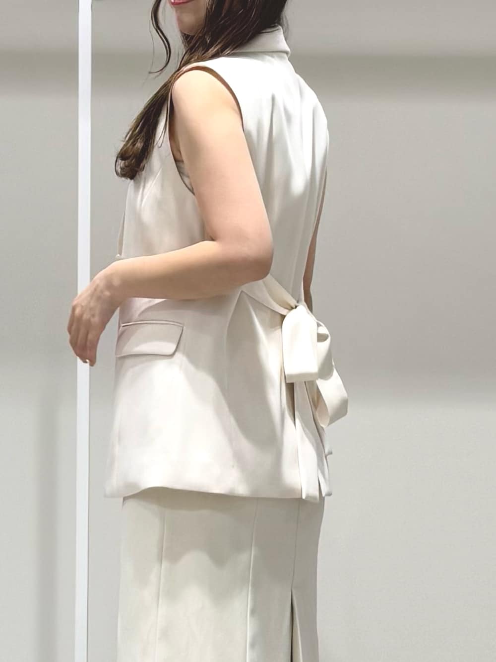 ホワイト系のワンピース、ベージュ系のサンダル、ホワイト系のベストを着用したレディースの春コーディネートの6枚目の写真