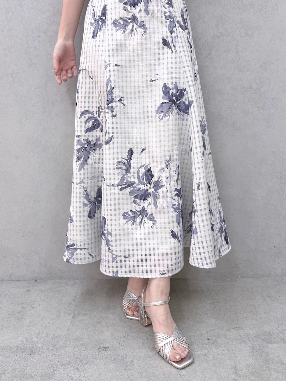 ブルー系のニット/セーター、ブルー系のスカート、シルバー系のサンダルを着用したレディースの春コーディネートの6枚目の写真