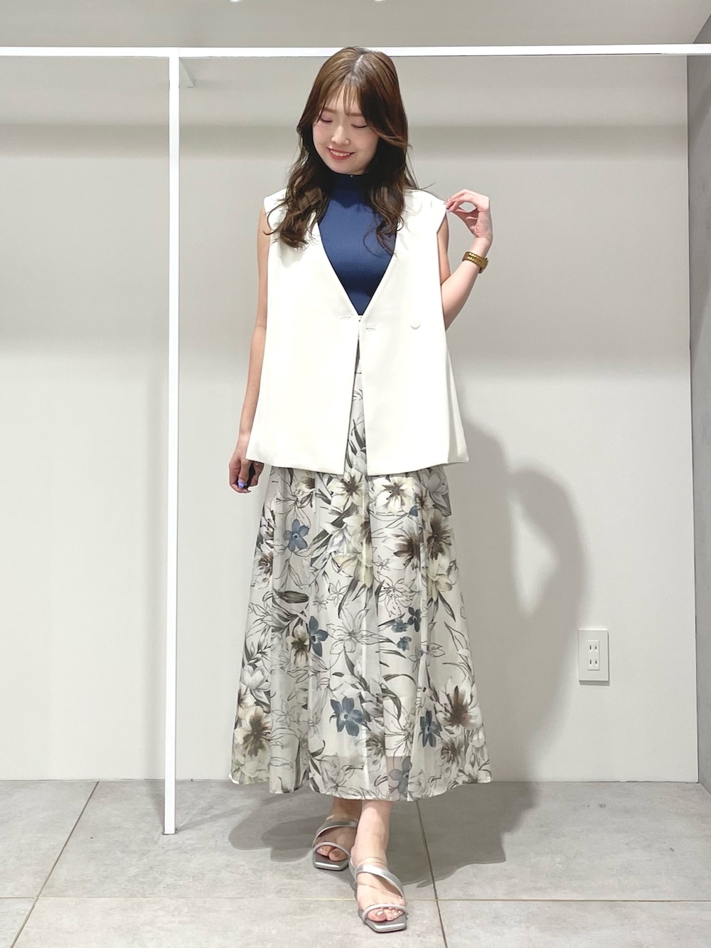 ホワイト系のベスト、グリーン系のスカート、ブルー系のニット/セーターを着用したレディースの春コーディネートの6枚目の写真