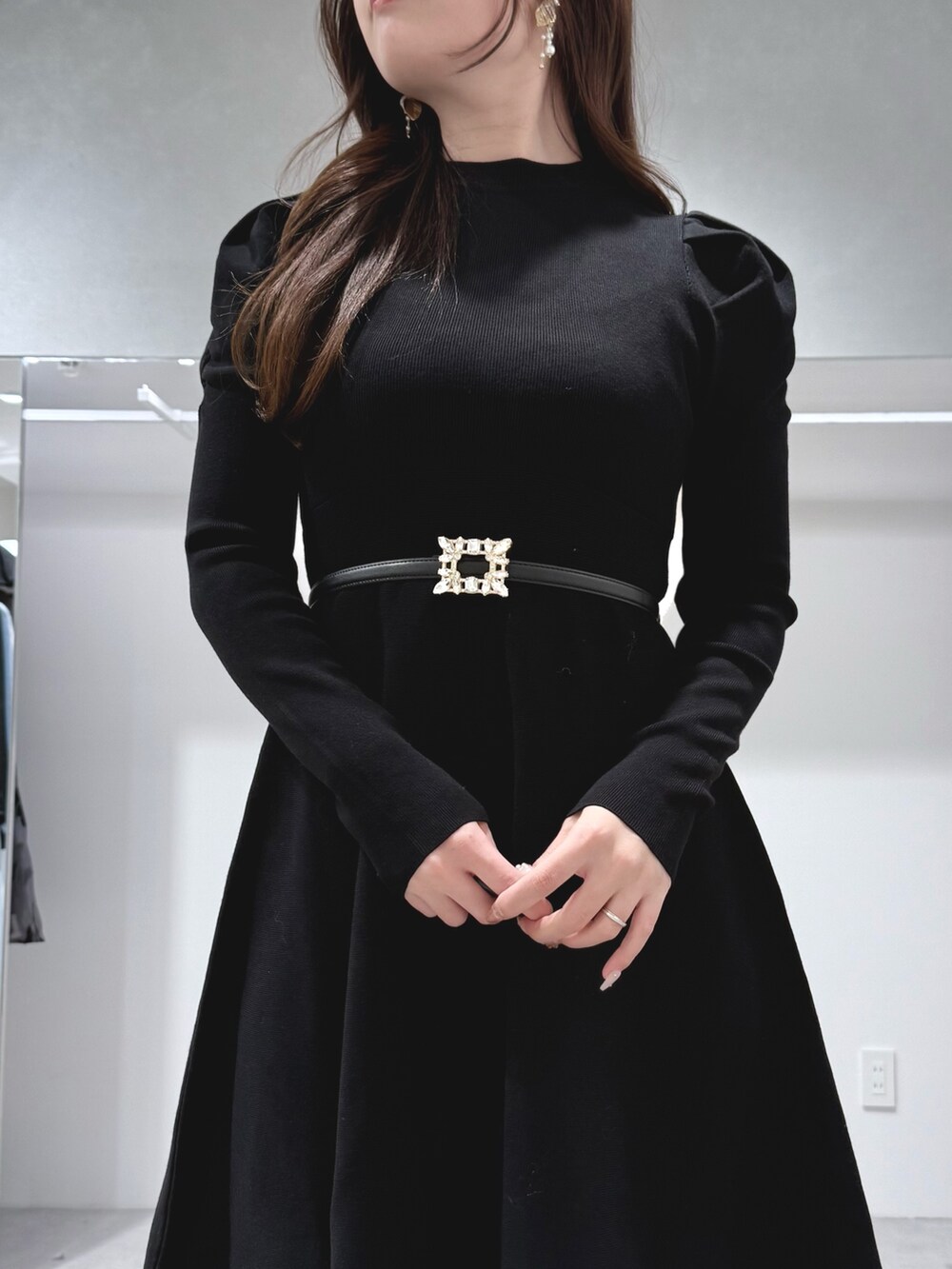 ホワイト系のハンドバッグ、ブラック系のブーツ、ブラック系のワンピースを着用したレディースの冬コーディネートの5枚目の写真