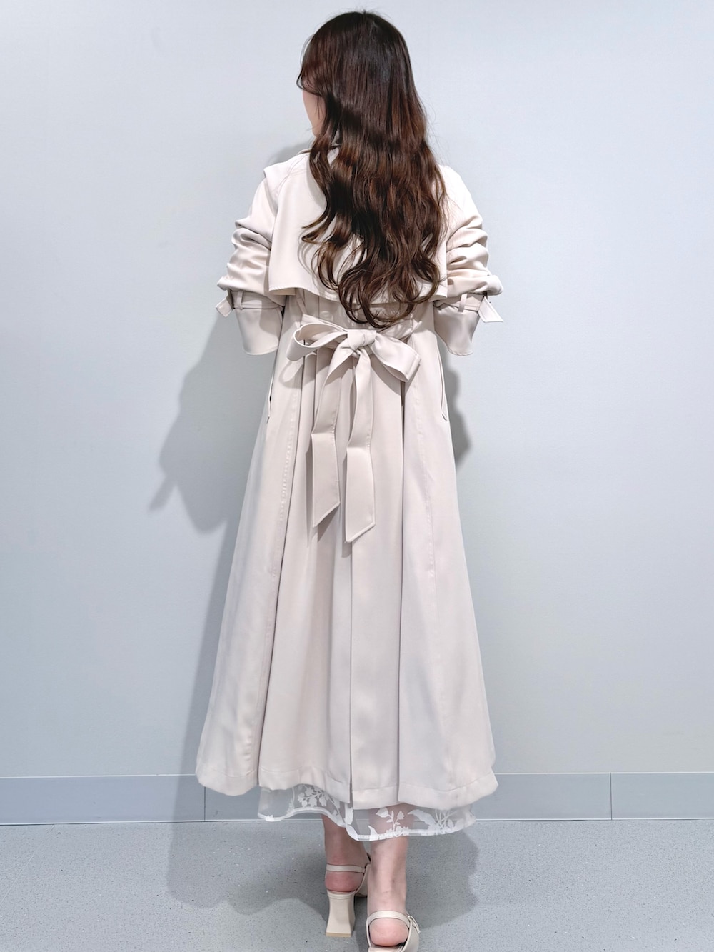 ベージュ系のワンピース、ホワイト系のパンプス、ホワイト系のトレンチコートを着用したレディースの冬コーディネートの4枚目の写真