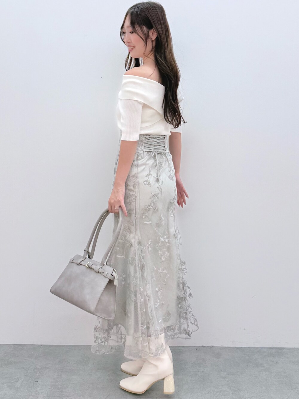 ホワイト系のニット/セーター、ホワイト系のブーツ、グリーン系のスカートを着用したレディースの秋コーディネートの3枚目の写真