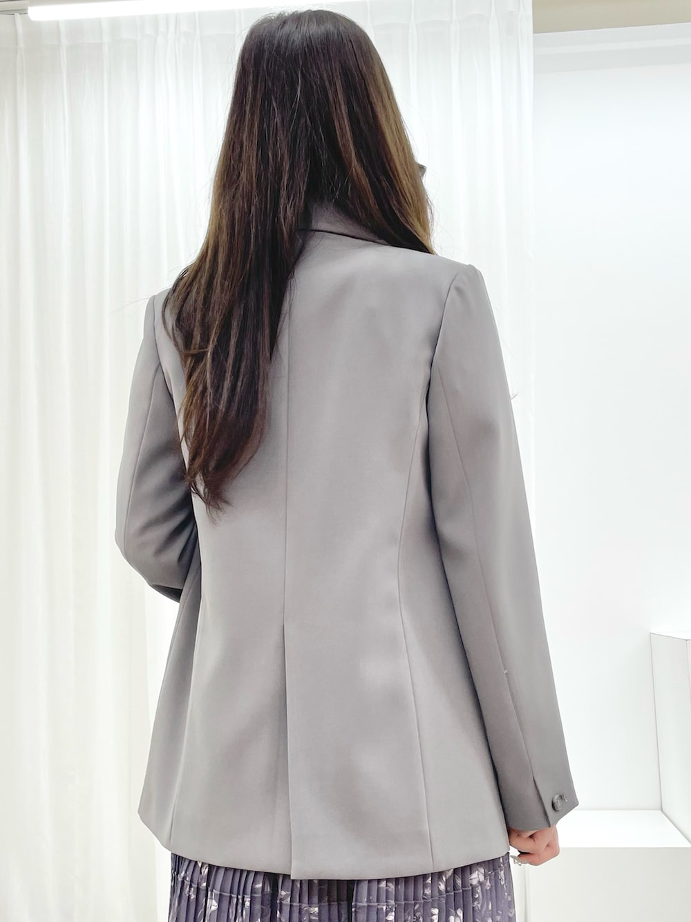 グレー系のワンピース、ブラック系のブーツ、グレー系のテーラードジャケットを着用したレディースの秋コーディネートの5枚目の写真