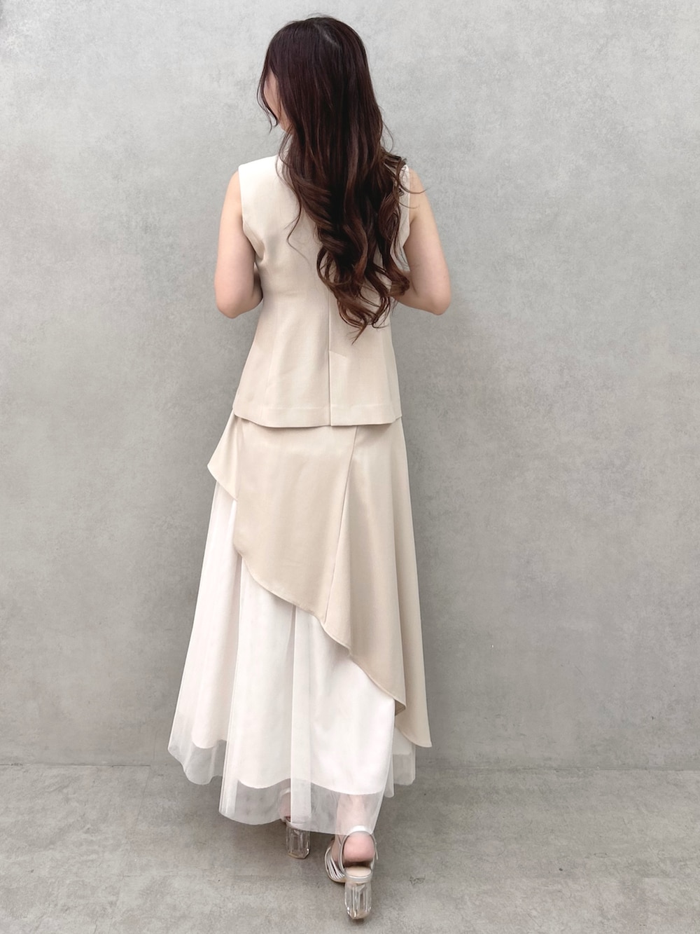 シルバー系のサンダル、ベージュ系のスカート、ベージュ系のベストを着用したレディースの春コーディネートの4枚目の写真