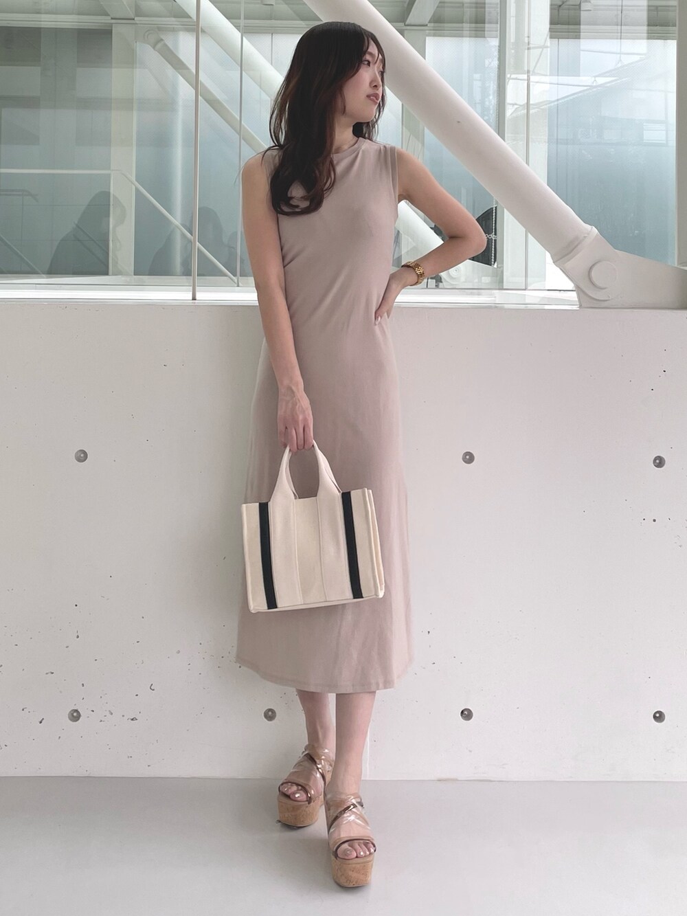 ホワイト系のハンドバッグ、ブラウン系のサンダル、ベージュ系のワンピースを着用したレディースの春コーディネートの3枚目の写真