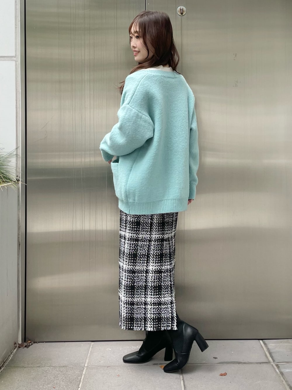 グリーン系のカーディガン/ボレロ、ブラック系のスカート、ブラック系のブーツを着用したレディースの秋コーディネートの3枚目の写真