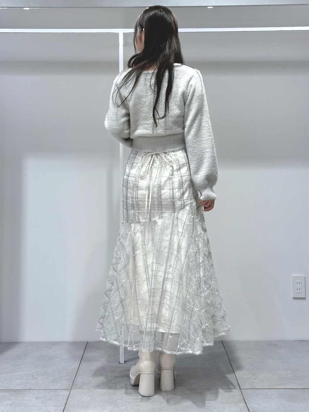 グレー系のカーディガン/ボレロ、ホワイト系のスカート、ホワイト系のブーツを着用したレディースの秋コーディネートの3枚目の写真