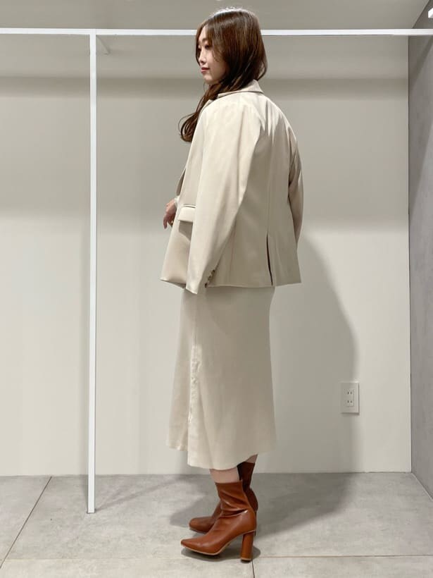 ブラウン系のブーツ、ベージュ系のテーラードジャケット、ホワイト系のワンピースを着用したレディースの秋コーディネートの4枚目の写真
