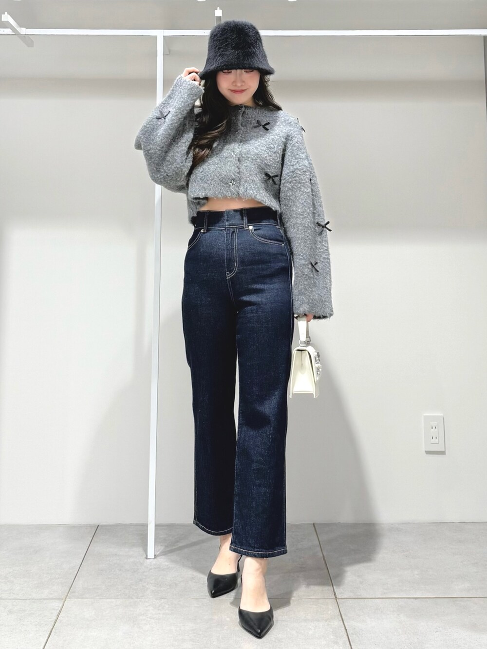 グレー系のカーディガン/ボレロ、ブルー系のデニムパンツ、ホワイト系のショルダーバッグを着用したレディースの冬コーディネートの2枚目の写真