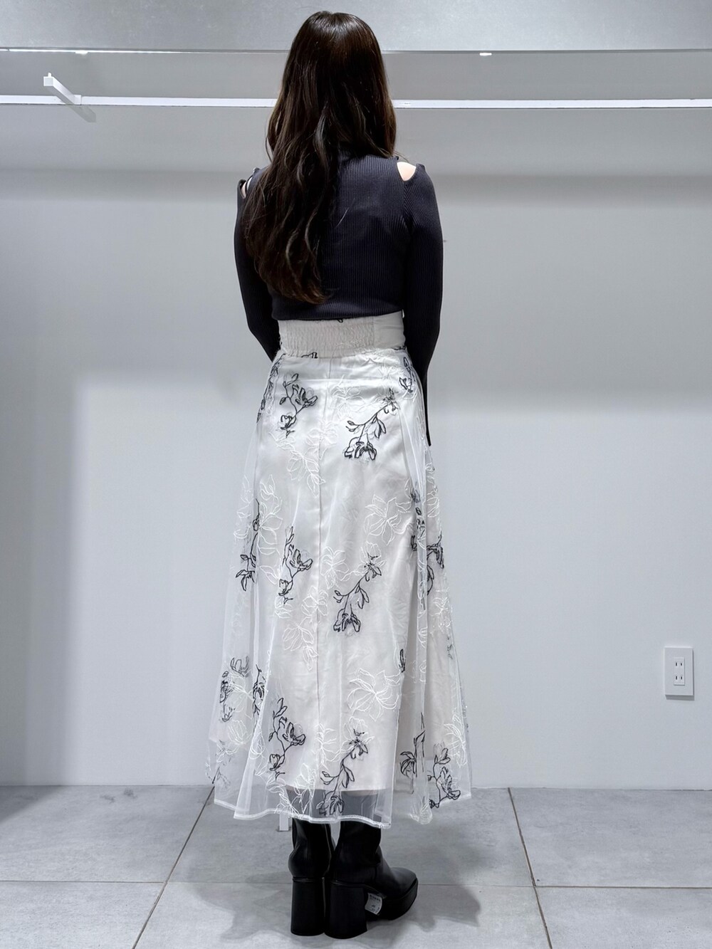 グレー系のニット/セーター、ブラック系のブーツ、ホワイト系のスカートを着用したレディースの冬コーディネートの4枚目の写真