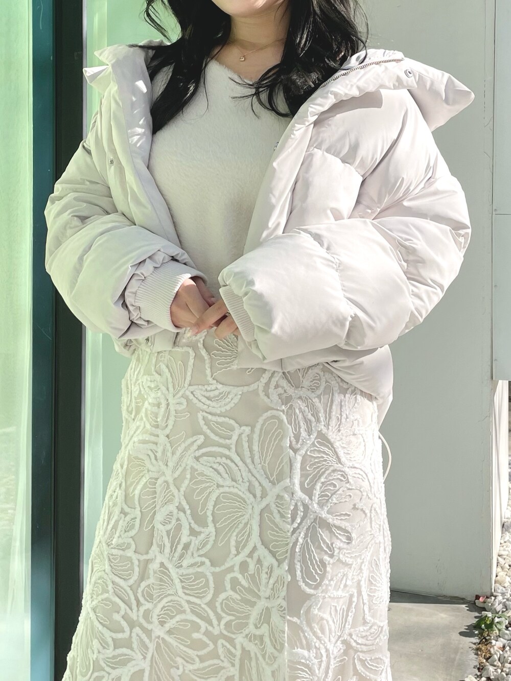 ホワイト系のダウンジャケット/コート、ホワイト系のニット/セーター、ホワイト系のスカートを着用したレディースの冬コーディネートの3枚目の写真