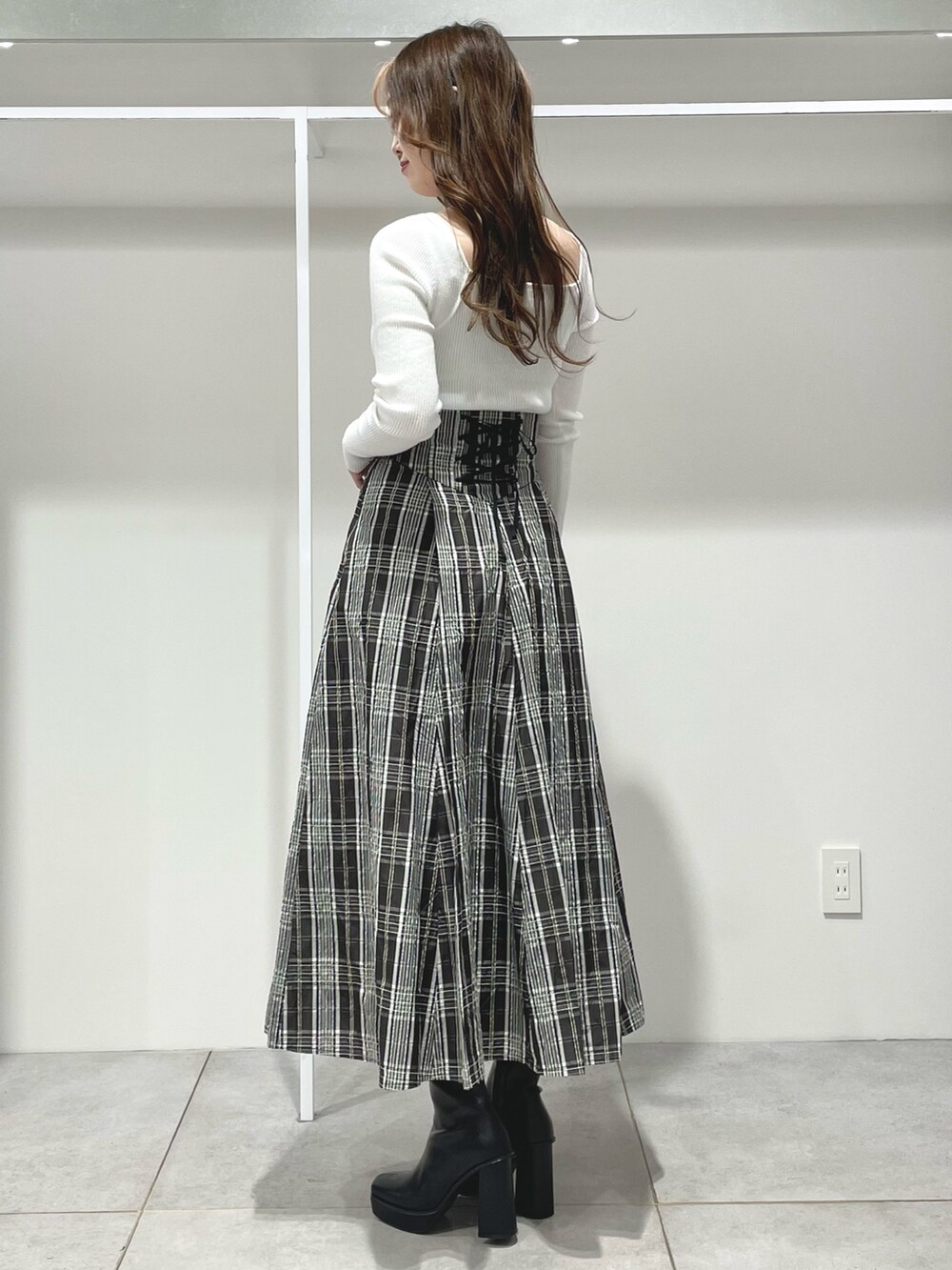 ブラック系のスカート、ブラック系のブーツ、ホワイト系のニット/セーターを着用したレディースの秋コーディネートの8枚目の写真