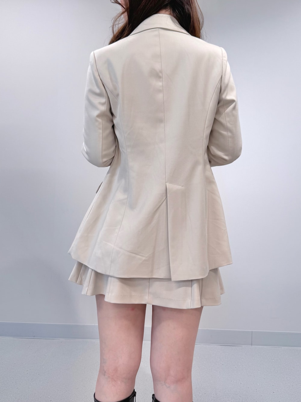 ホワイト系のテーラードジャケット、ブラック系のブーツ、ホワイト系のスカートを着用したレディースの冬コーディネートの6枚目の写真