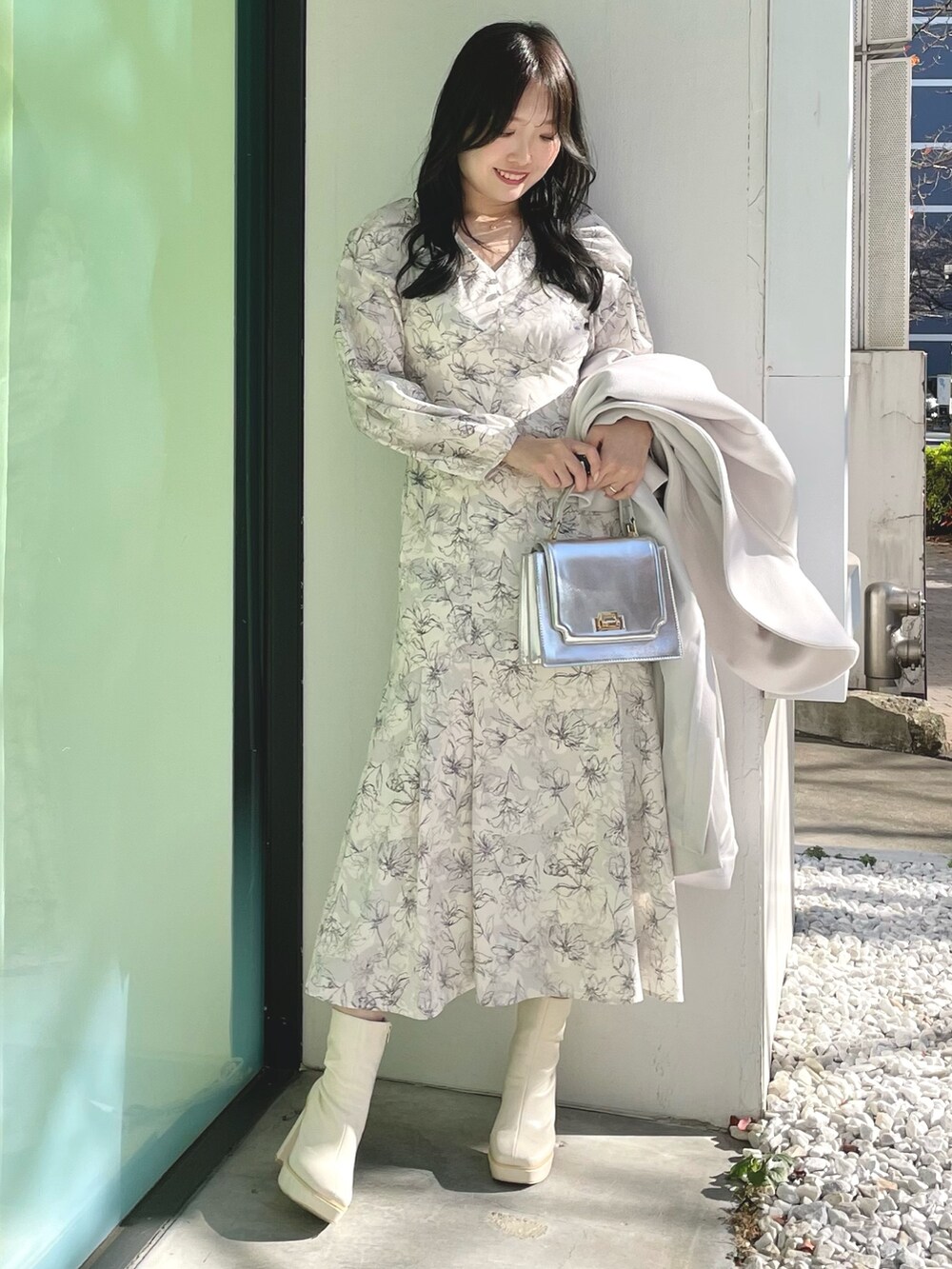 シルバー系のハンドバッグ、ホワイト系のブーツ、ホワイト系のチェスターコートを着用したレディースの冬コーディネートの5枚目の写真