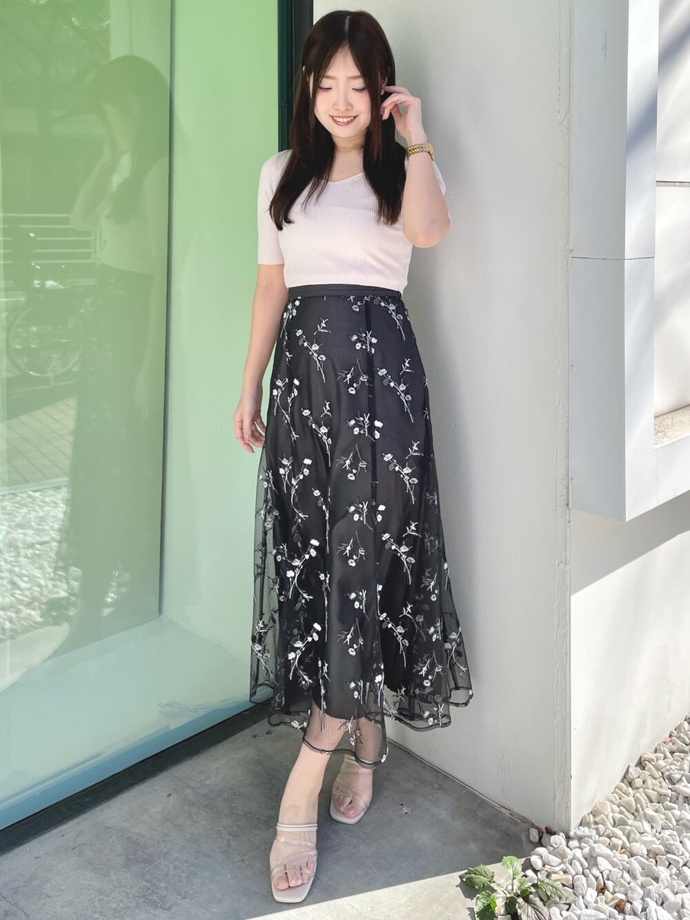 ピンク系のニット/セーター、グレー系のスカート、ホワイト系のサンダルを着用したレディースの春コーディネートの2枚目の写真