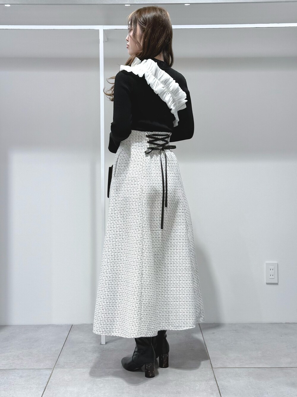 ブラック系のニット/セーター、ブラック系のハンドバッグ、ブラック系のブーツを着用したレディースの秋コーディネートの3枚目の写真