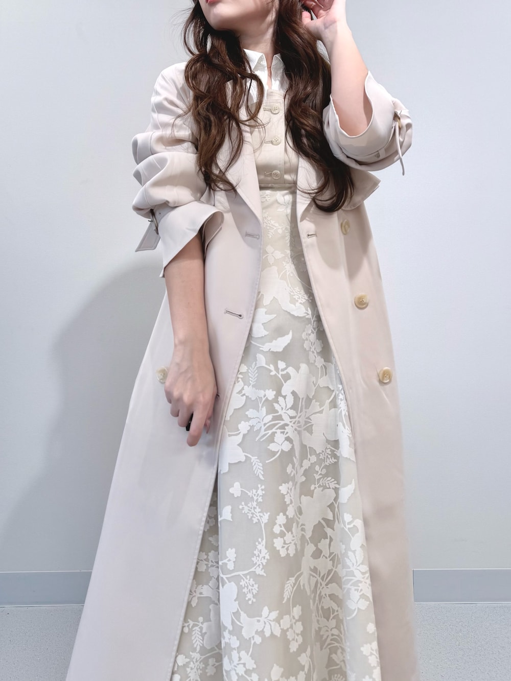 ベージュ系のワンピース、ホワイト系のパンプス、ホワイト系のトレンチコートを着用したレディースの冬コーディネートの5枚目の写真