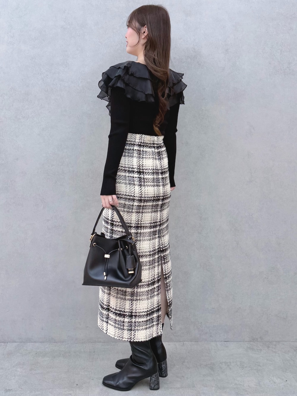ブラック系のニット/セーター、ホワイト系のスカート、ブラック系のブーツを着用したレディースの冬コーディネートの2枚目の写真