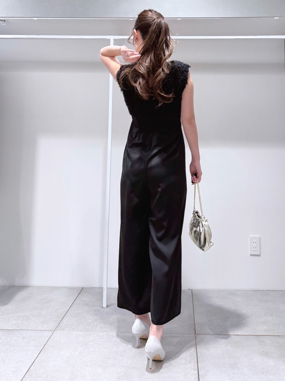 ブラック系のドレス、ゴールド系のショルダーバッグ、シルバー系のパンプスを着用したレディースの冬コーディネートの4枚目の写真