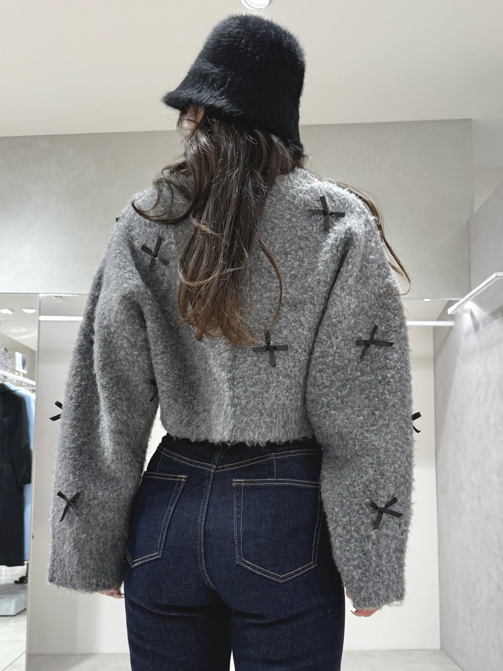 グレー系のカーディガン/ボレロ、ブルー系のデニムパンツ、ホワイト系のショルダーバッグを着用したレディースの冬コーディネートの7枚目の写真