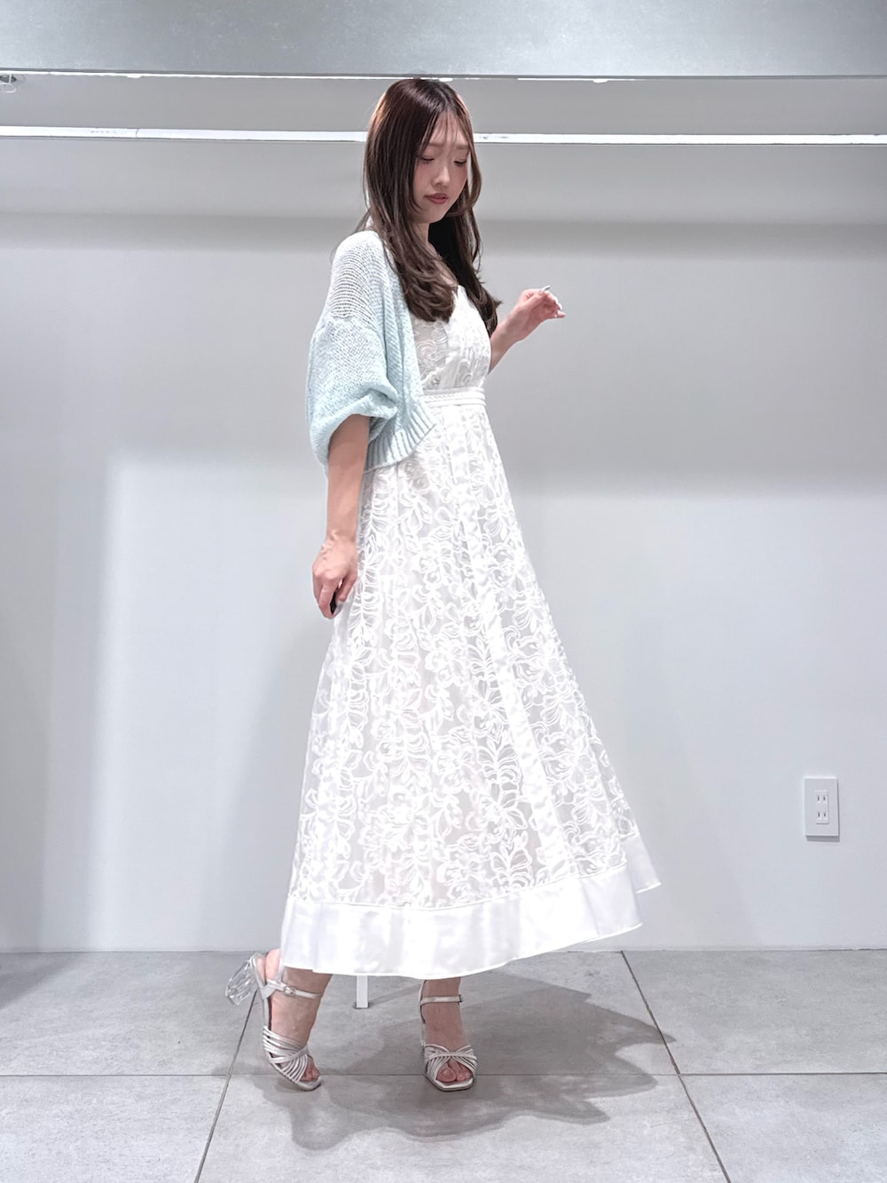 ブルー系のカーディガン/ボレロ、ホワイト系のワンピース、シルバー系のサンダルを着用したレディースの春コーディネートの2枚目の写真
