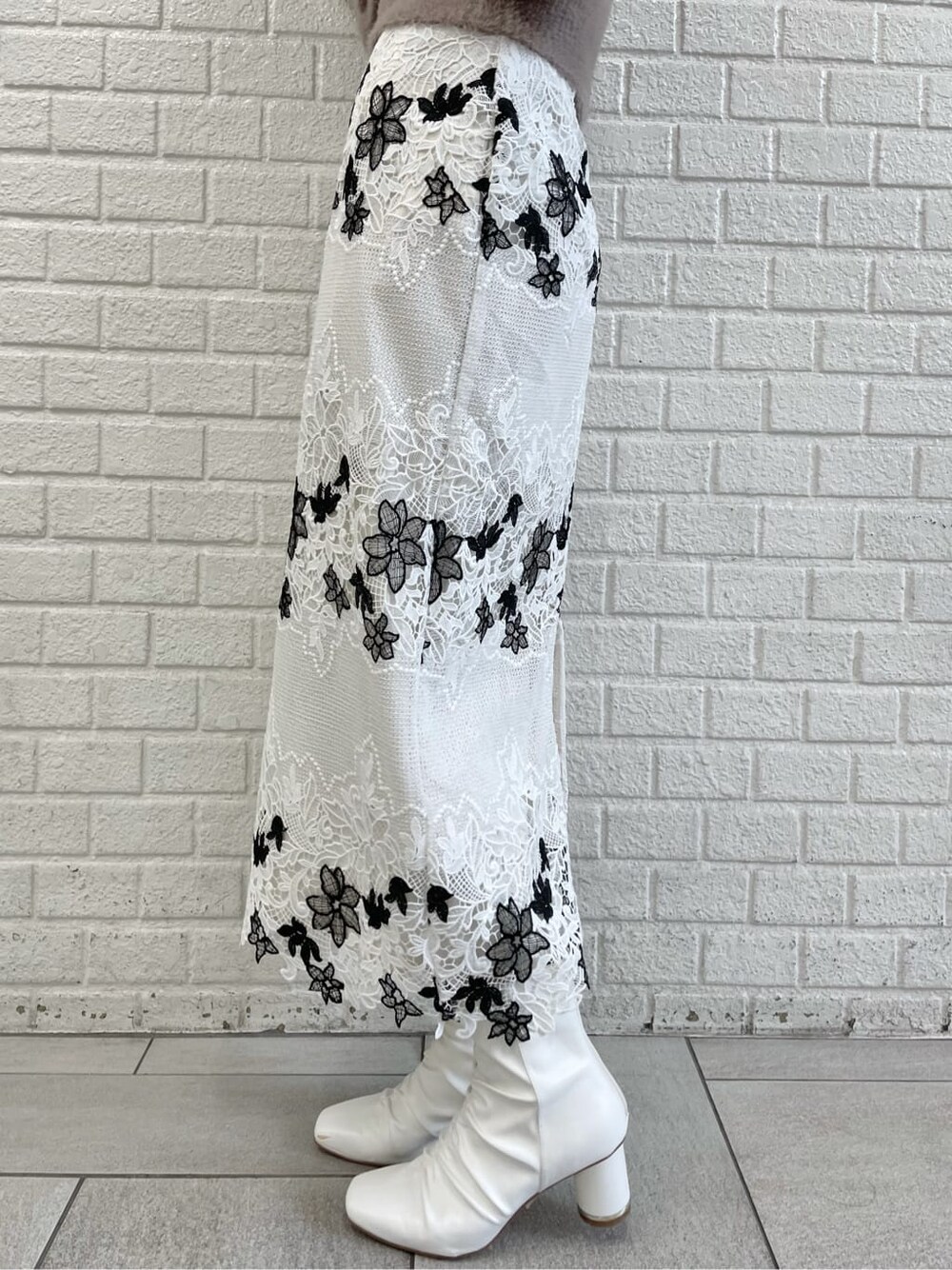 ブラウン系のニット/セーター、ホワイト系のスカート、ホワイト系のその他シューズを着用したレディースの秋コーディネートの7枚目の写真