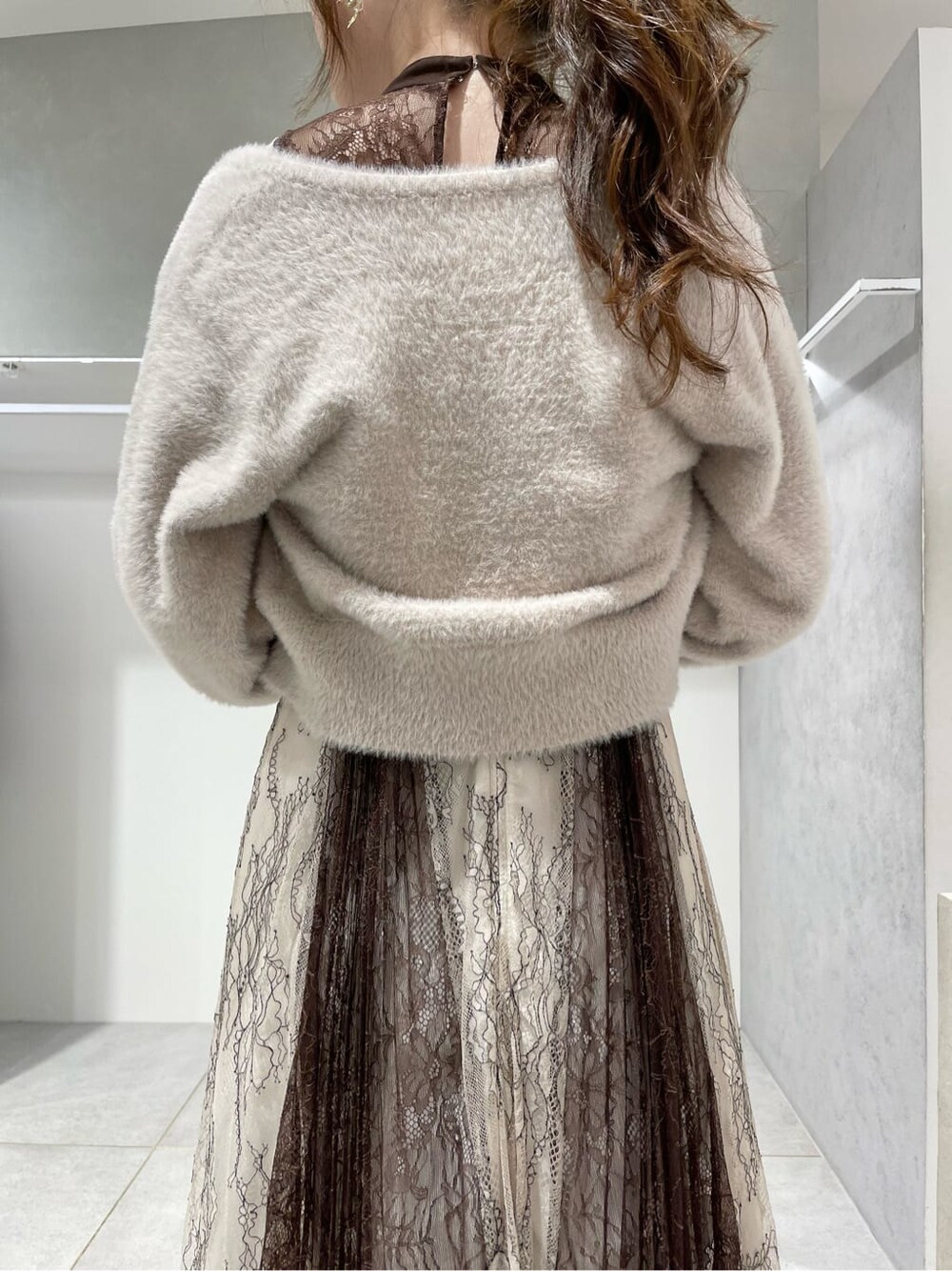 ブラック系のパンプス、ホワイト系のワンピース、ベージュ系のカーディガン/ボレロを着用したレディースの秋コーディネートの4枚目の写真