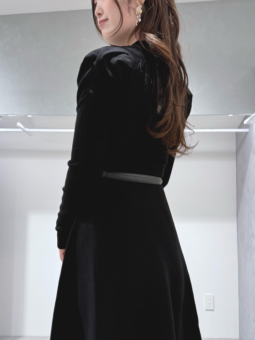 ホワイト系のハンドバッグ、ブラック系のブーツ、ブラック系のワンピースを着用したレディースの冬コーディネートの6枚目の写真