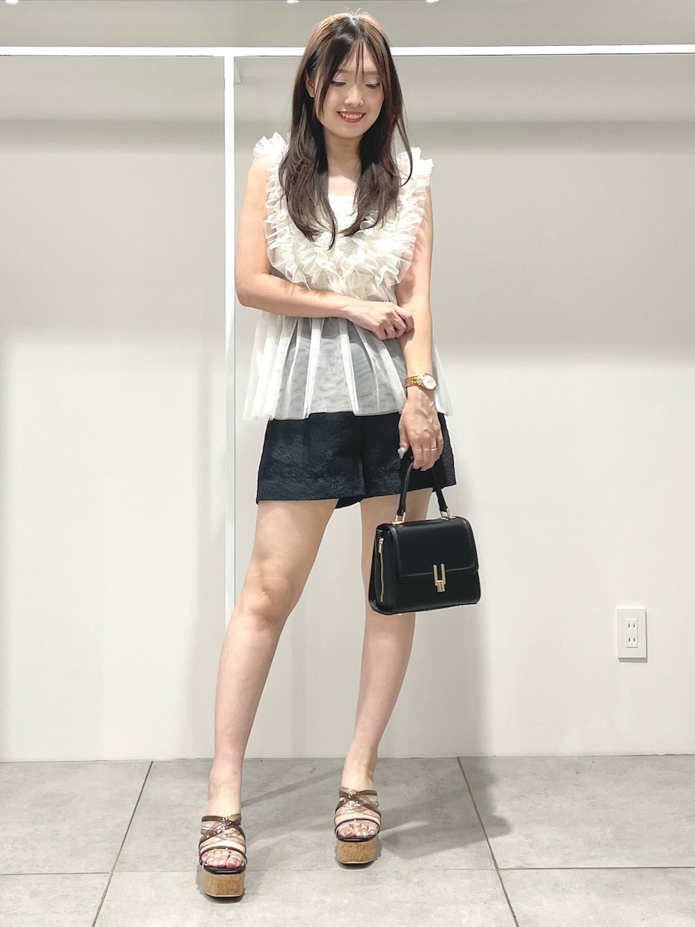 ブラック系のサンダル、ブラック系のショルダーバッグ、ホワイト系のシャツ/ブラウスを着用したレディースの夏コーディネートの2枚目の写真