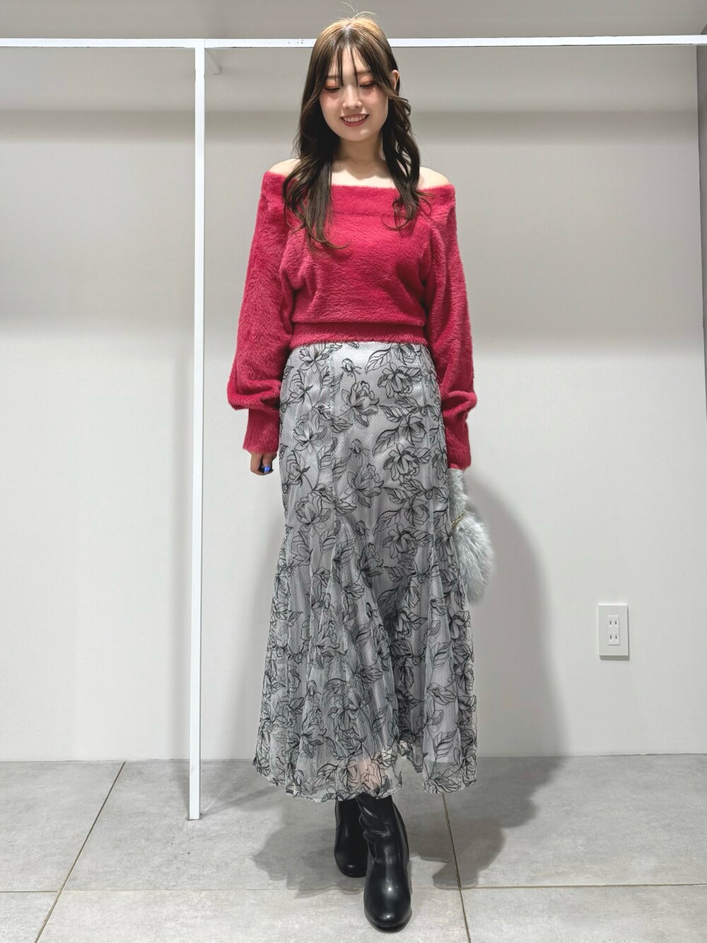 レッド系のニット/セーター、グレー系のハンドバッグ、グレー系のスカートを着用したレディースの秋コーディネートの2枚目の写真