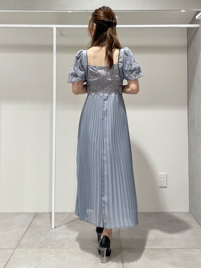 ブラック系のパンプス、ブルー系のワンピース、シルバー系のイヤリングを着用したレディースの秋コーディネートの4枚目の写真