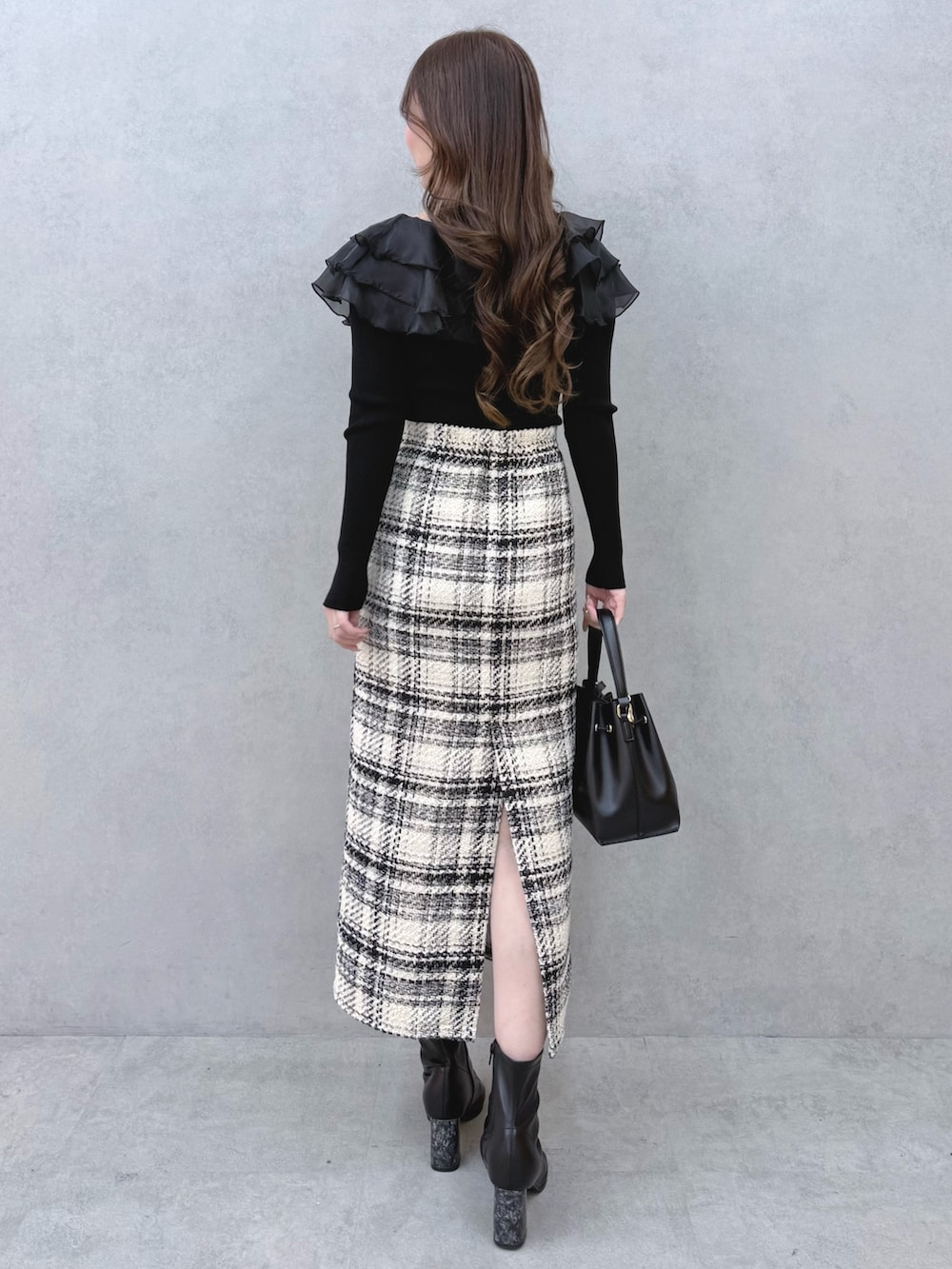 ブラック系のニット/セーター、ホワイト系のスカート、ブラック系のブーツを着用したレディースの冬コーディネートの3枚目の写真