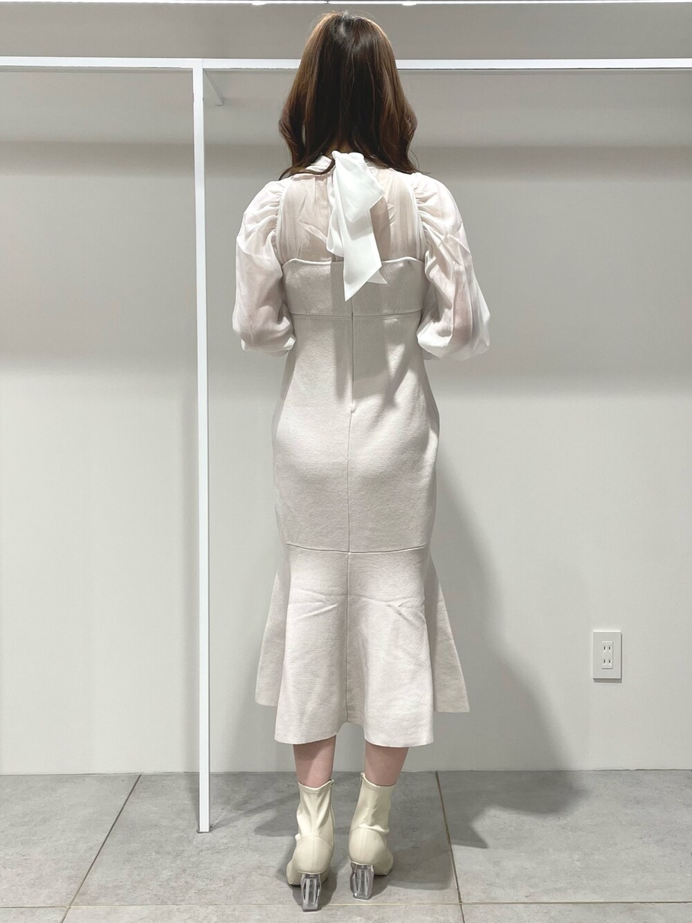 ホワイト系のチェスターコート、ピンク系のハンドバッグ、ホワイト系のワンピースを着用したレディースの冬コーディネートの8枚目の写真