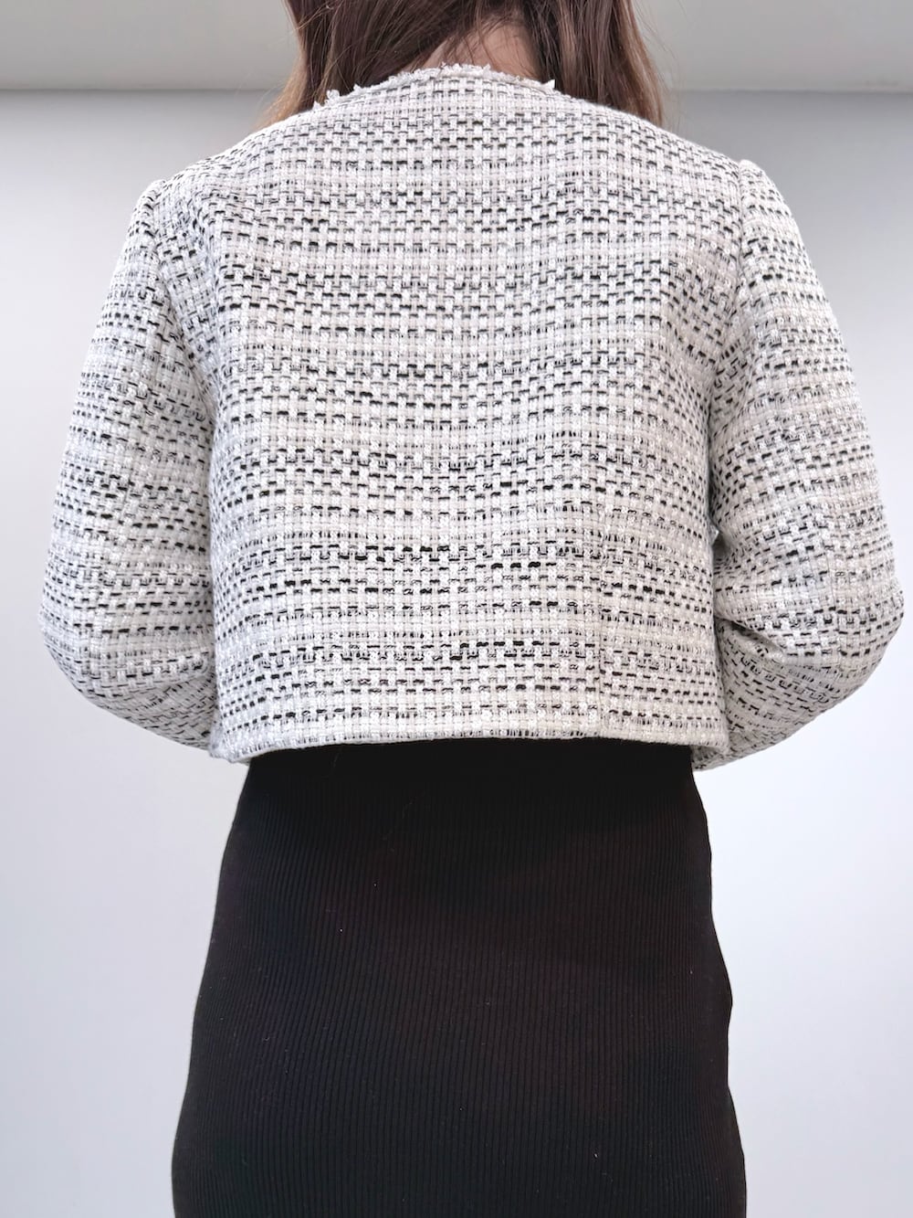 ホワイト系のテーラードジャケット、ブラック系のワンピース、ブラック系のブーツを着用したレディースの冬コーディネートの6枚目の写真