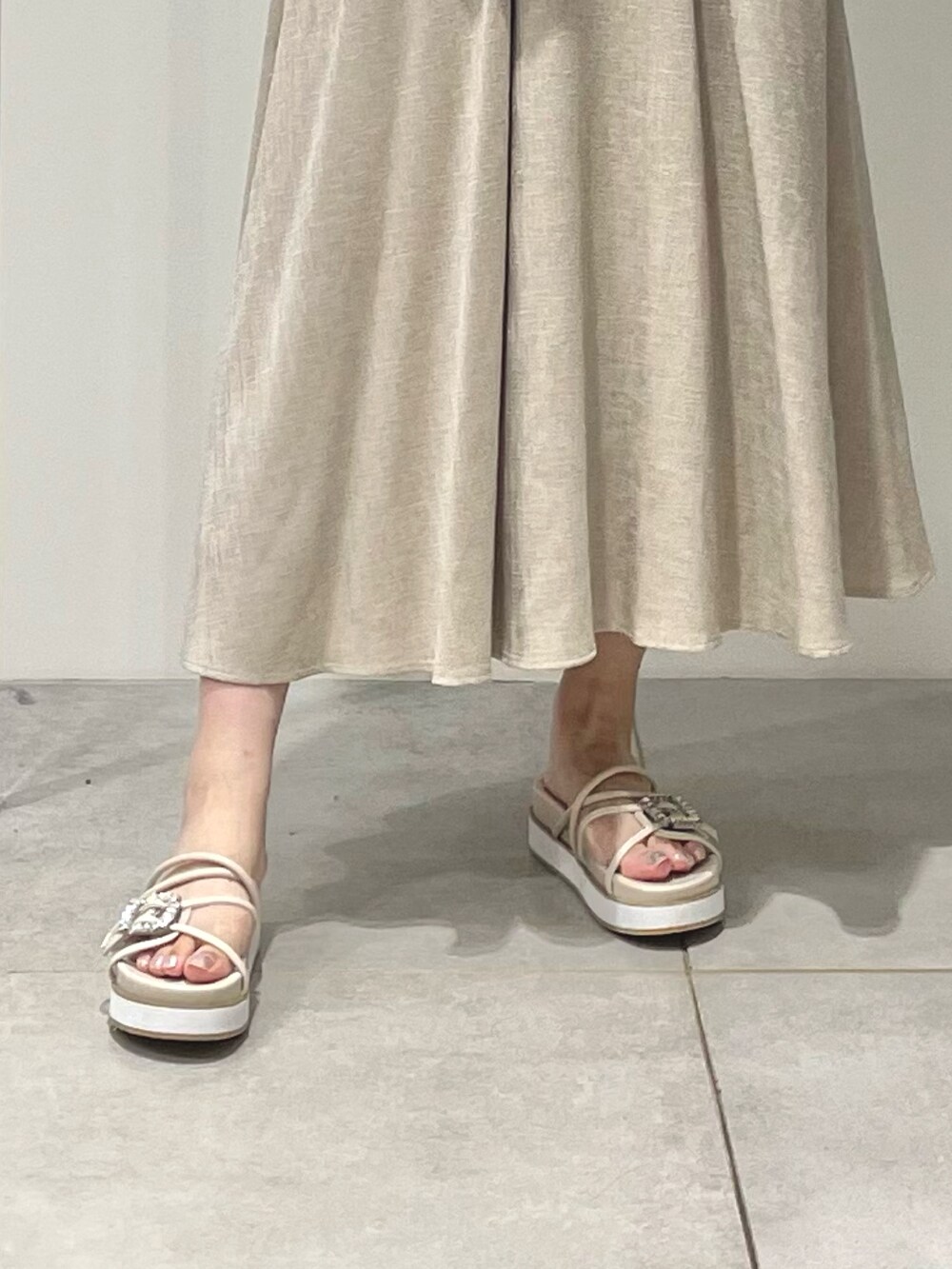 ベージュ系のワンピース、ホワイト系のカーディガン/ボレロ、ベージュ系のサンダルを着用したレディースの夏コーディネートの7枚目の写真