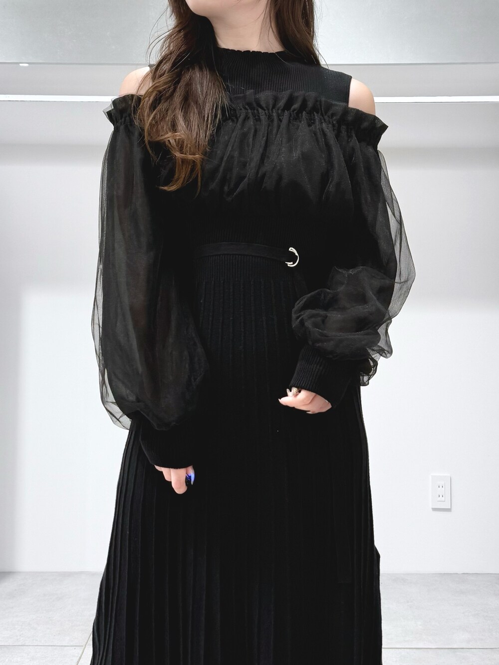 ホワイト系のハンドバッグ、ブラック系のワンピース、ブラック系のブーツを着用したレディースの秋コーディネートの5枚目の写真