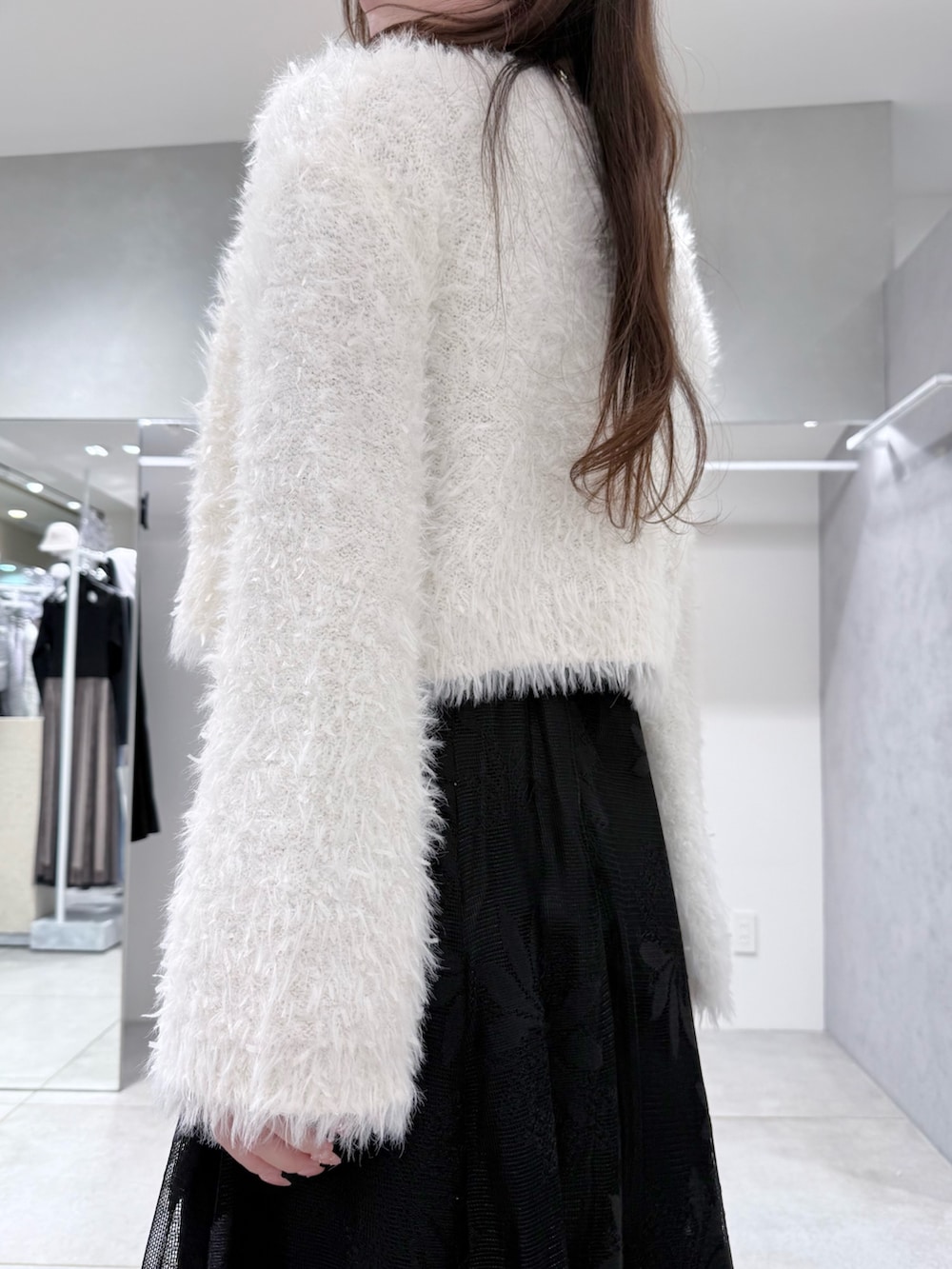 ブラック系のワンピース、ホワイト系のカーディガン/ボレロ、ホワイト系のハンドバッグを着用したレディースの冬コーディネートの7枚目の写真