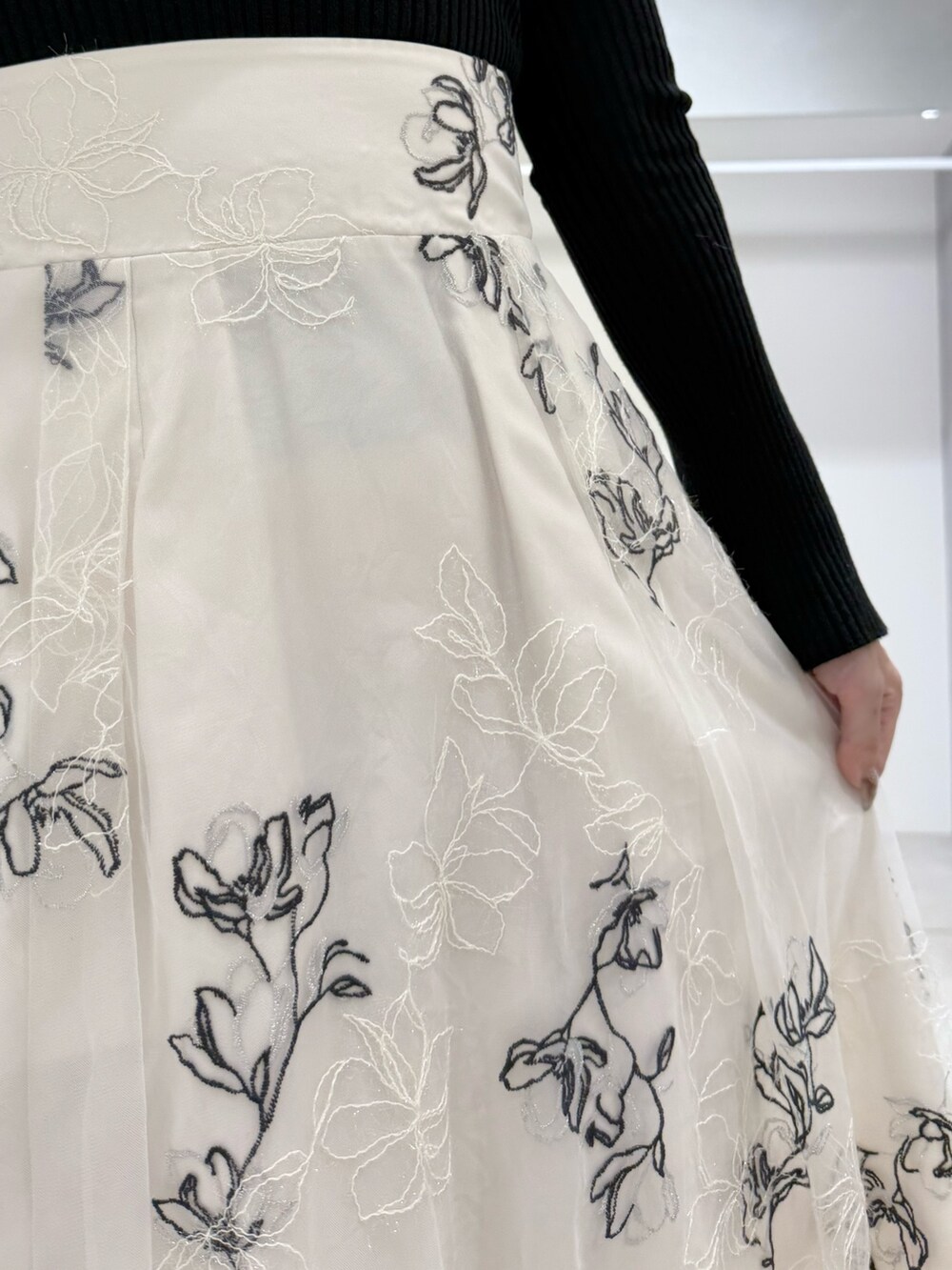 ブラック系のニット/セーター、ホワイト系のスカート、ブラック系のブーツを着用したレディースの冬コーディネートの7枚目の写真