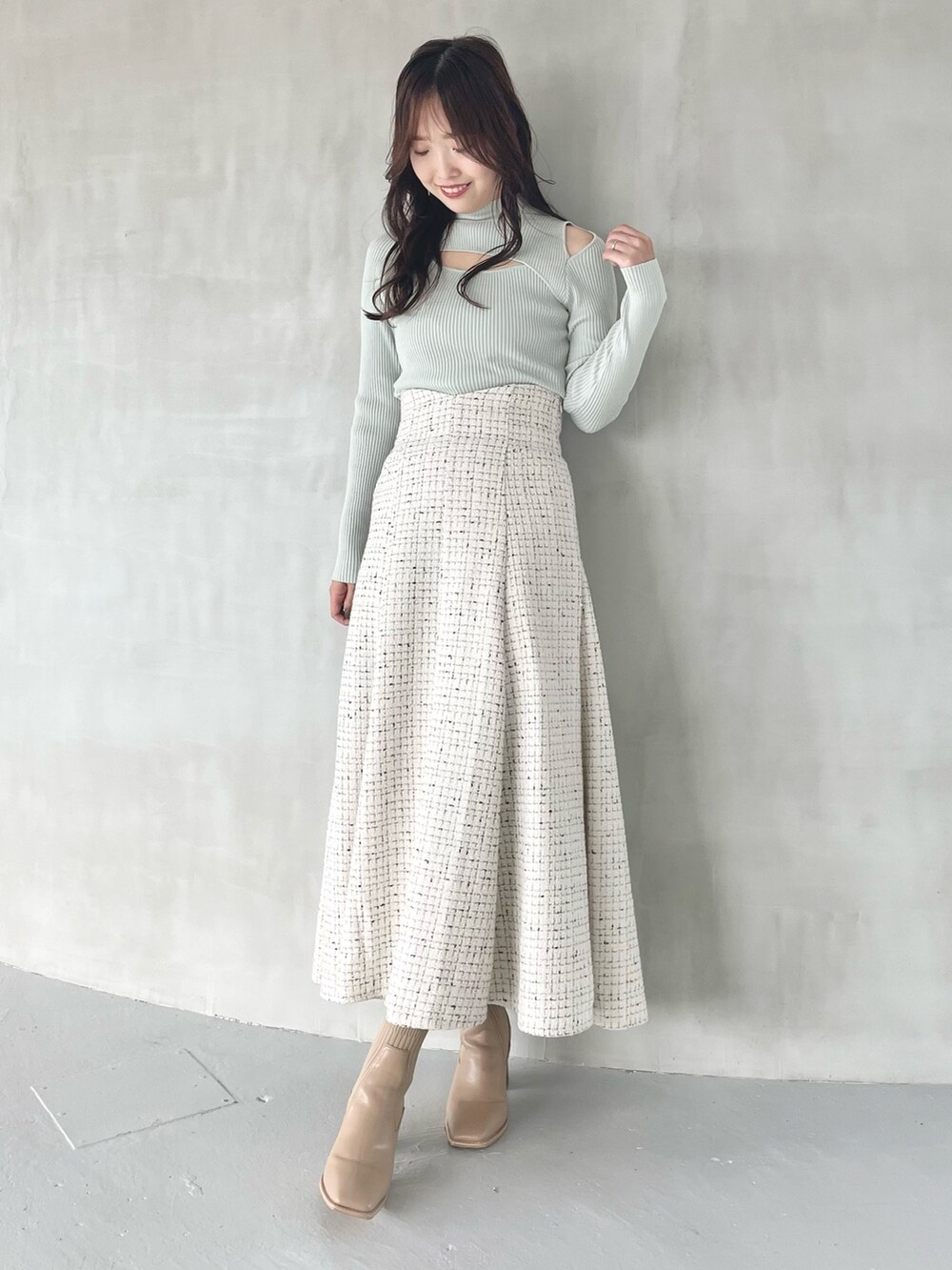 ホワイト系のスカート、ベージュ系のブーツ、グリーン系のニット/セーターを着用したレディースの秋コーディネートの3枚目の写真