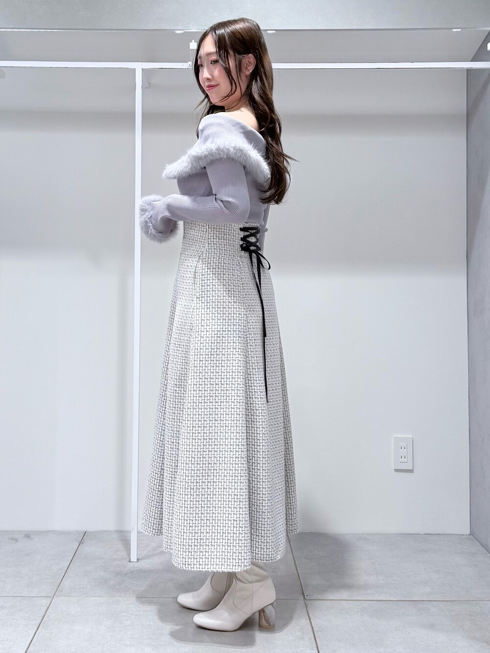 グレー系のニット/セーター、ホワイト系のスカート、ホワイト系のブーツを着用したレディースの冬コーディネートの4枚目の写真
