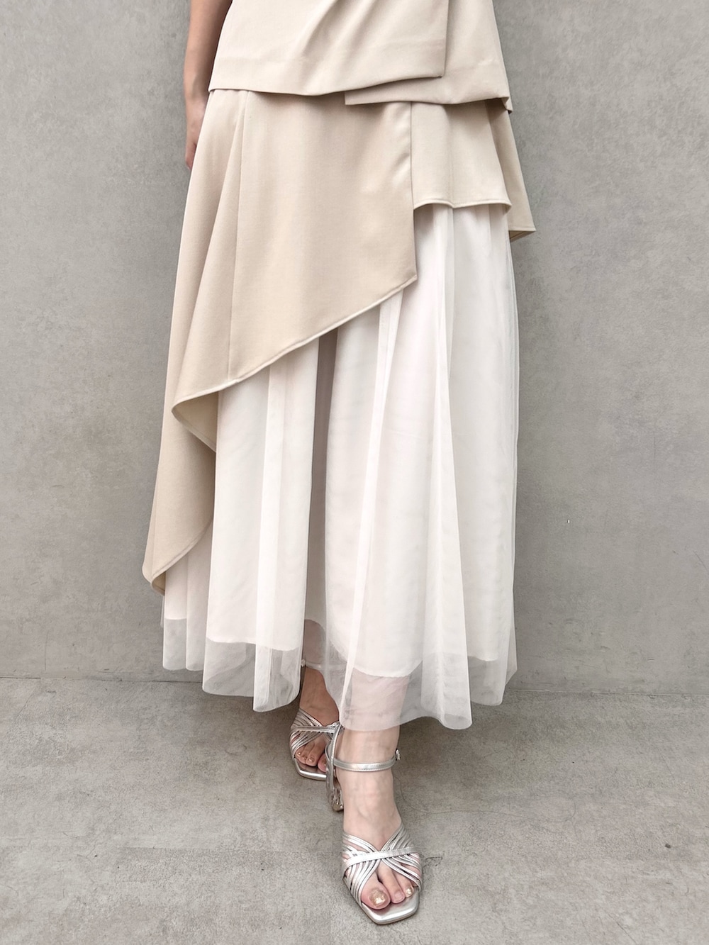シルバー系のサンダル、ベージュ系のスカート、ベージュ系のベストを着用したレディースの春コーディネートの7枚目の写真