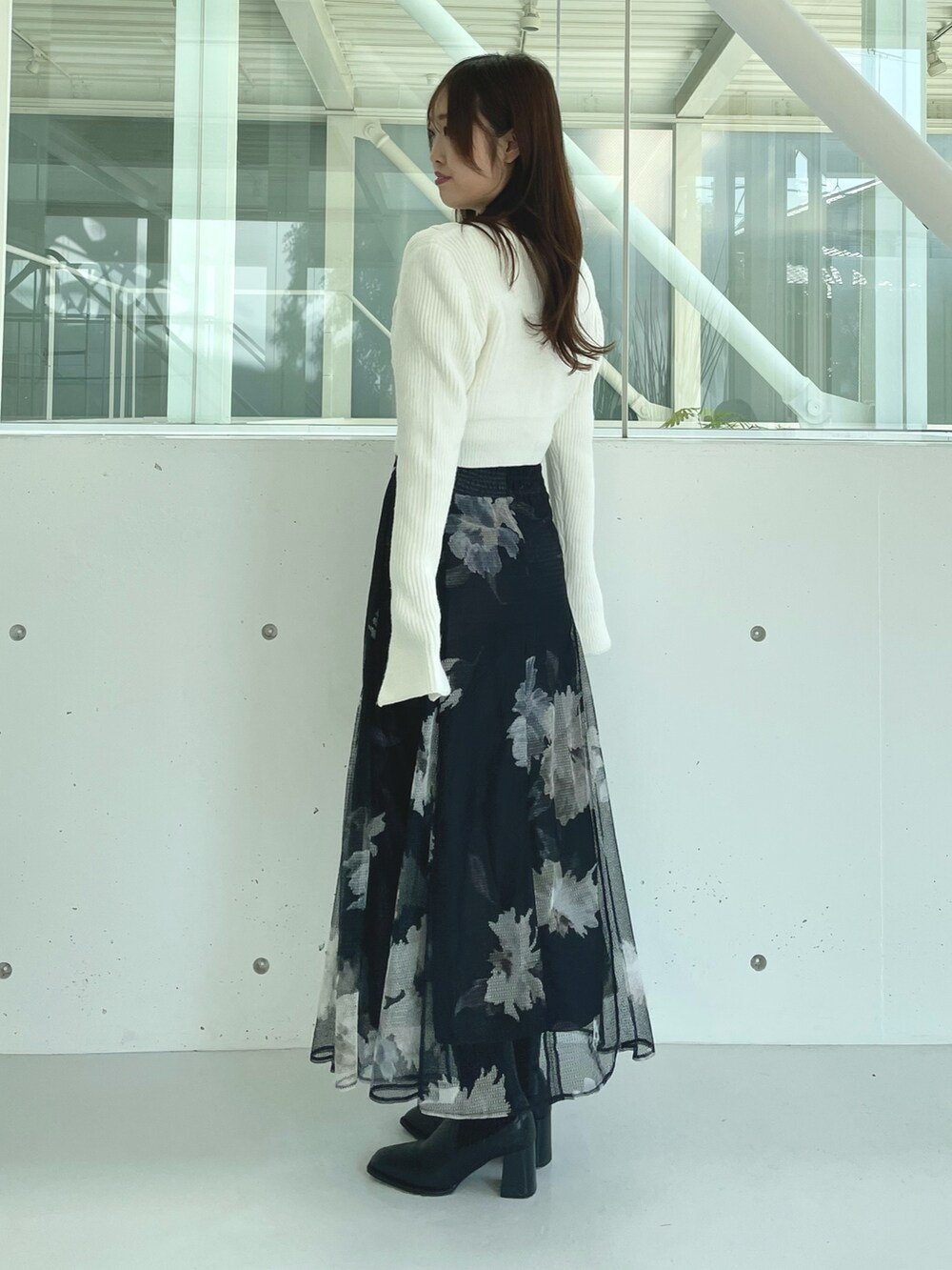 ブラック系のスカート、ブラック系のブーツ、ホワイト系のカーディガン/ボレロを着用したレディースの秋コーディネートの4枚目の写真