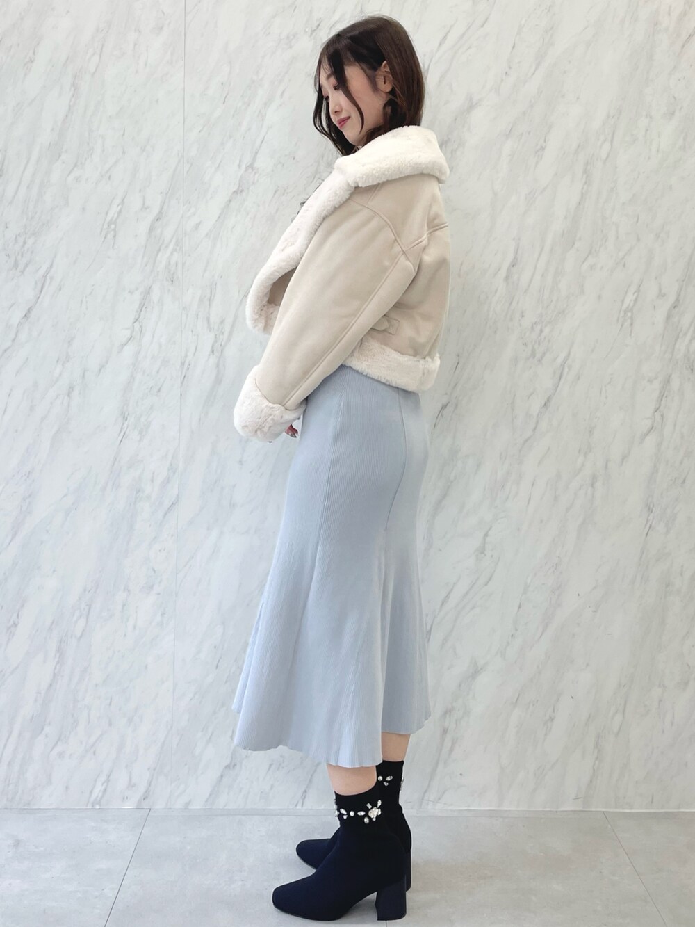 ブルー系のワンピース、ブラック系のブーツ、ベージュ系のムートンコートを着用したレディースの秋コーディネートの2枚目の写真