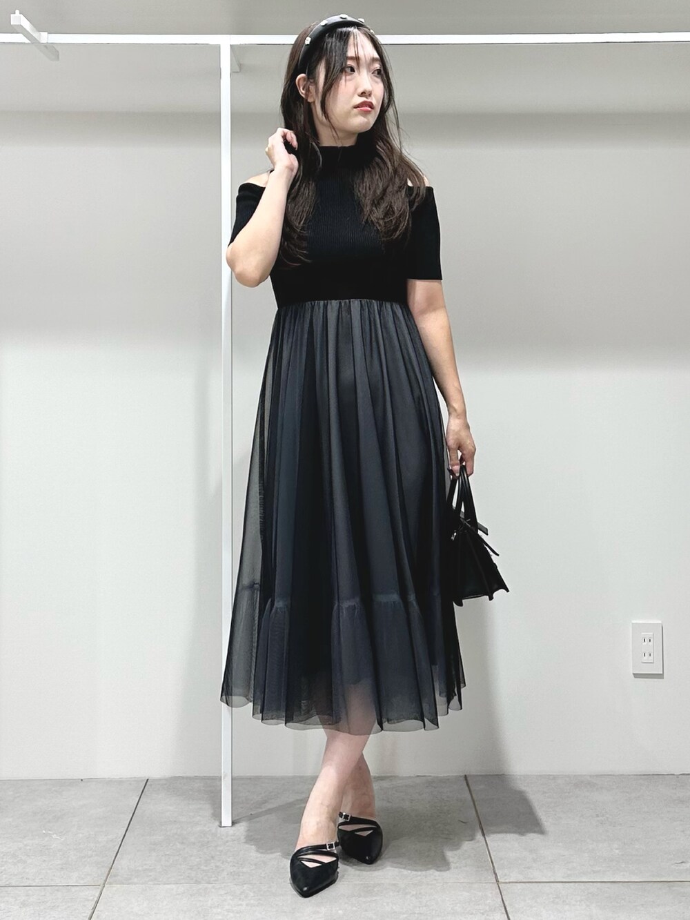 ブラック系のワンピース、ブラック系のショルダーバッグ、ブラック系のパンプスを着用したレディースの夏コーディネートの2枚目の写真