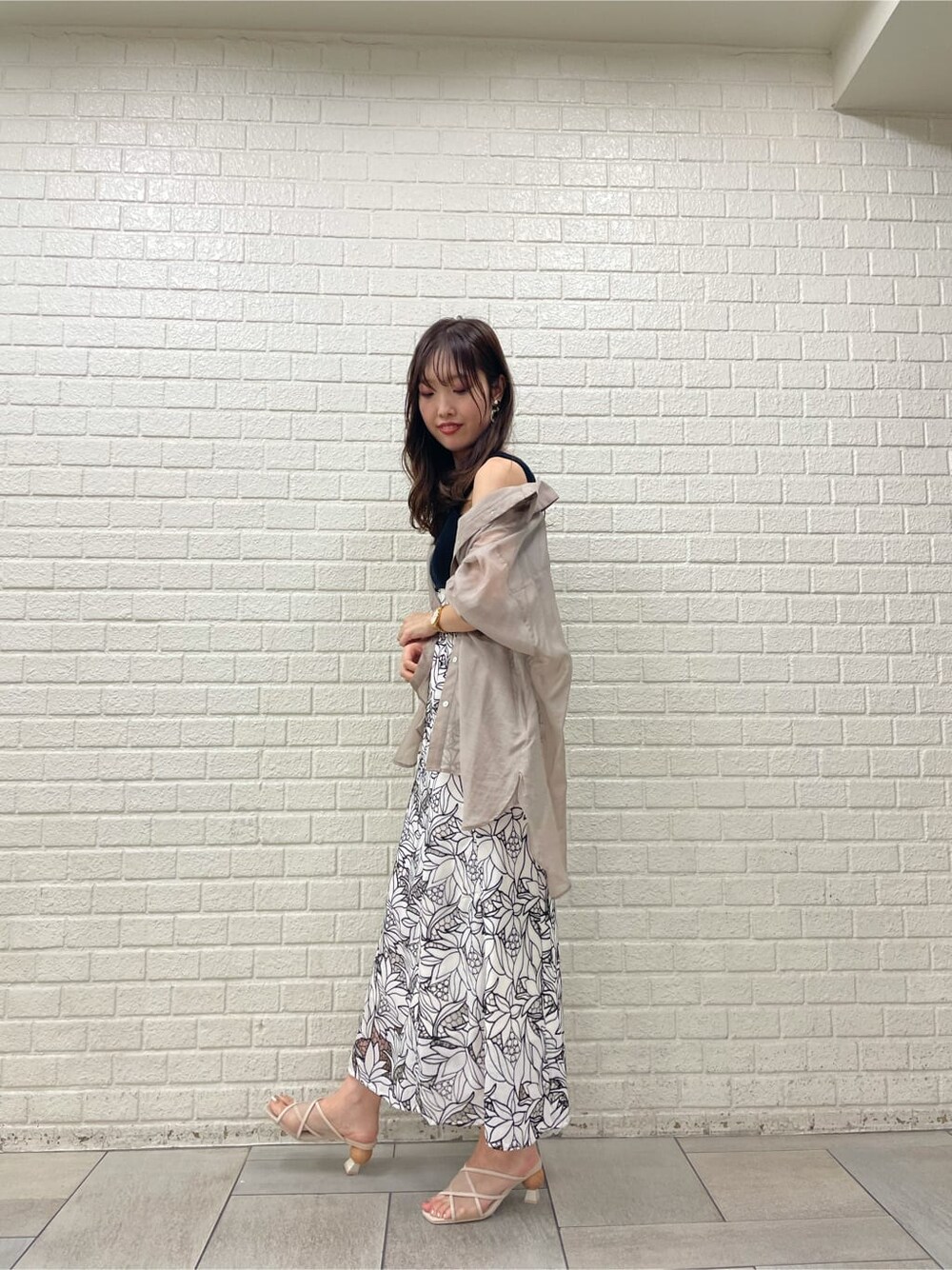 ベージュ系のサンダル、ブラック系のワンピース、ベージュ系のシャツ/ブラウスを着用したレディースの夏コーディネートの2枚目の写真