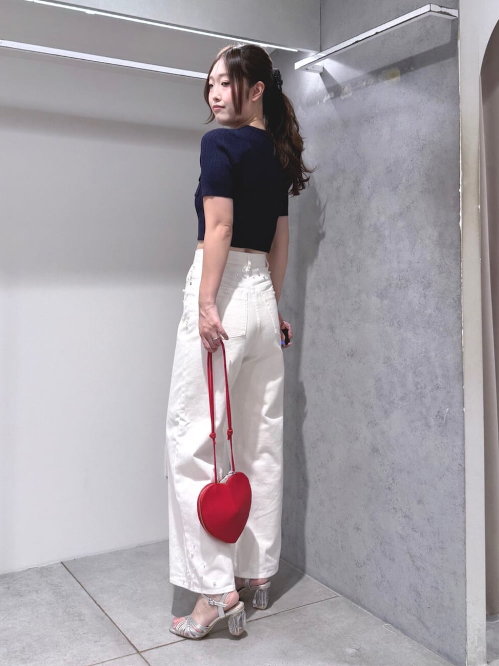 シルバー系のサンダル、ホワイト系のデニムパンツ、レッド系のショルダーバッグを着用したレディースの夏コーディネートの2枚目の写真