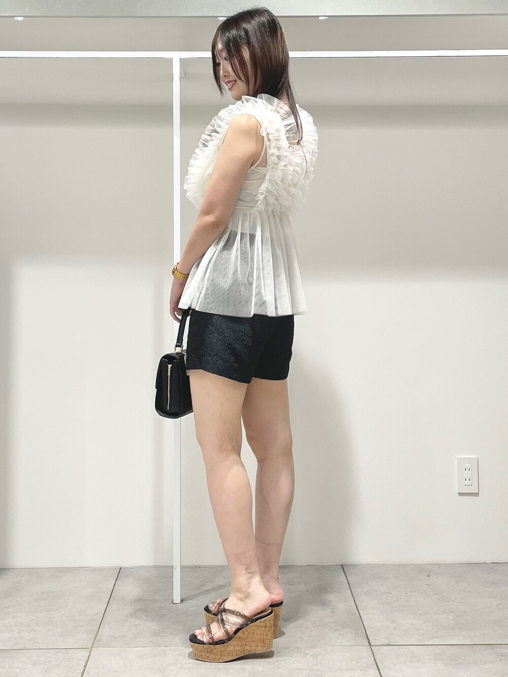 ブラック系のサンダル、ブラック系のショルダーバッグ、ホワイト系のシャツ/ブラウスを着用したレディースの夏コーディネートの3枚目の写真