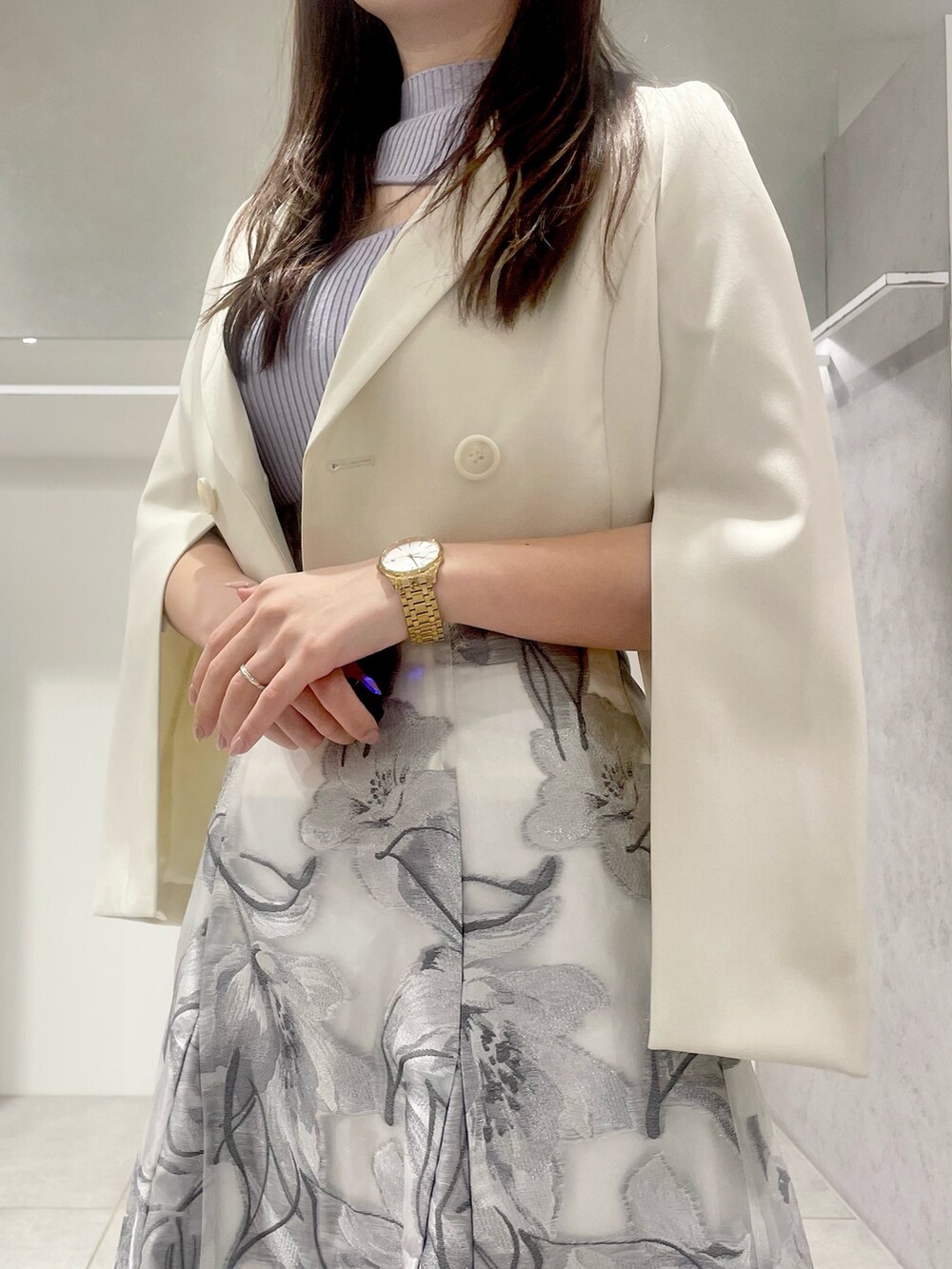 シルバー系のハンドバッグ、ホワイト系のテーラードジャケット、ブルー系のニット/セーターを着用したレディースの春コーディネートの4枚目の写真